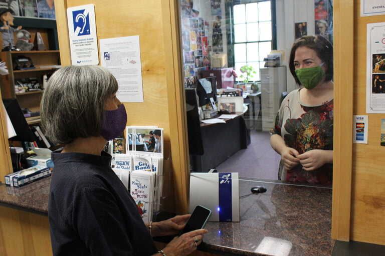 Two people at a ticket counter, with a portable hearing loop