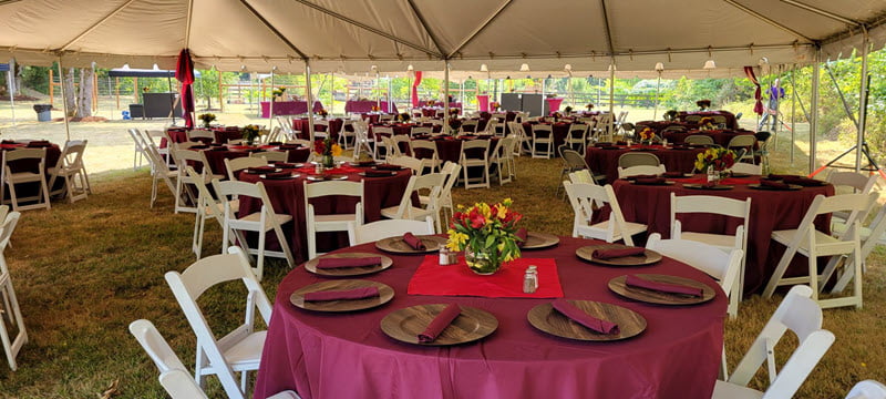 Underneath a tent canopy with round tables and chairs