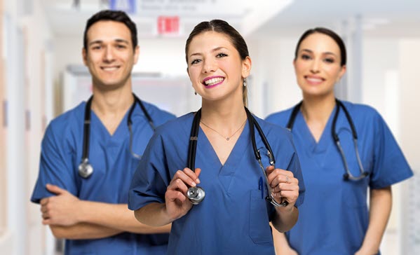 2 women and one man, each in blue scrubs with stethoscopes around their necks.