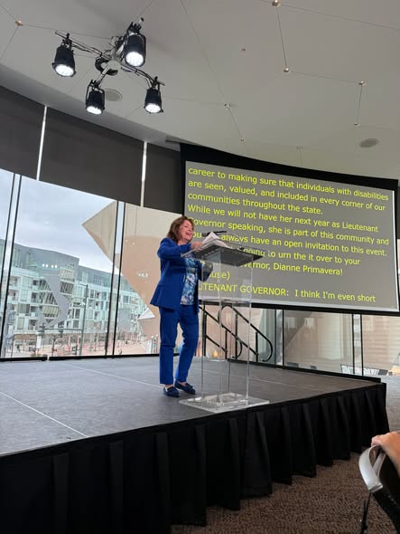 speaker on stage with a large screen displaying the captions