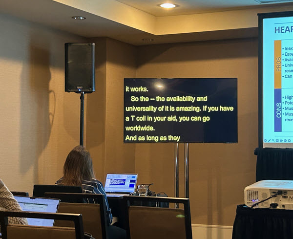 CART on second screen to the left of PowerPoint, with captioner in the front of the room