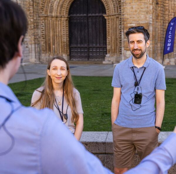 Two people on a tour using neckloops with FM/RF system. A tour guide's back is in the left part of the photo