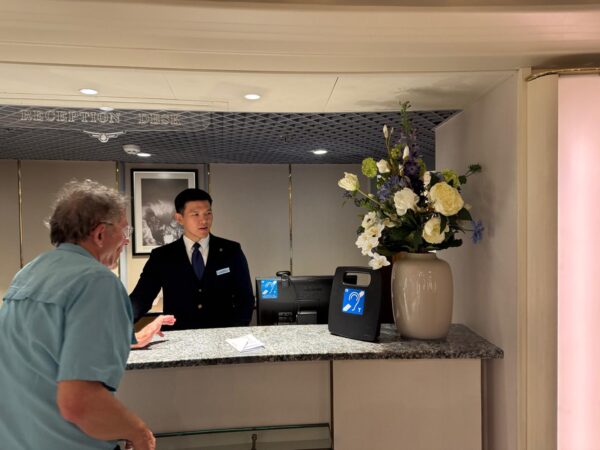 A portable service counter hearing loop on a cruise. A passenger is talking with a staff member