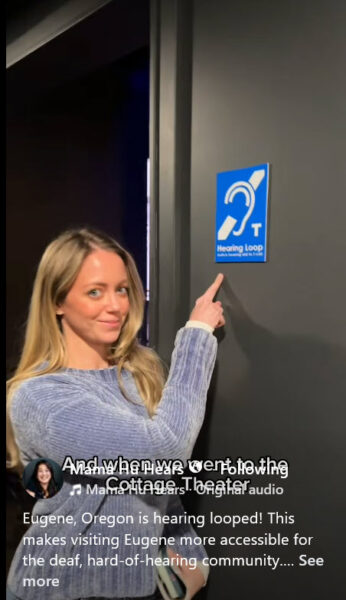 Woman pointing to hearing loop sign on the walll