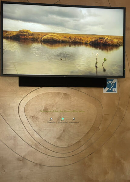 Screen with photo. Hearing loop sign in the lower right. 3 buttons to push for films