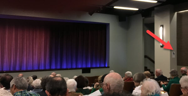 seniors in auditorium with hearing loop sign